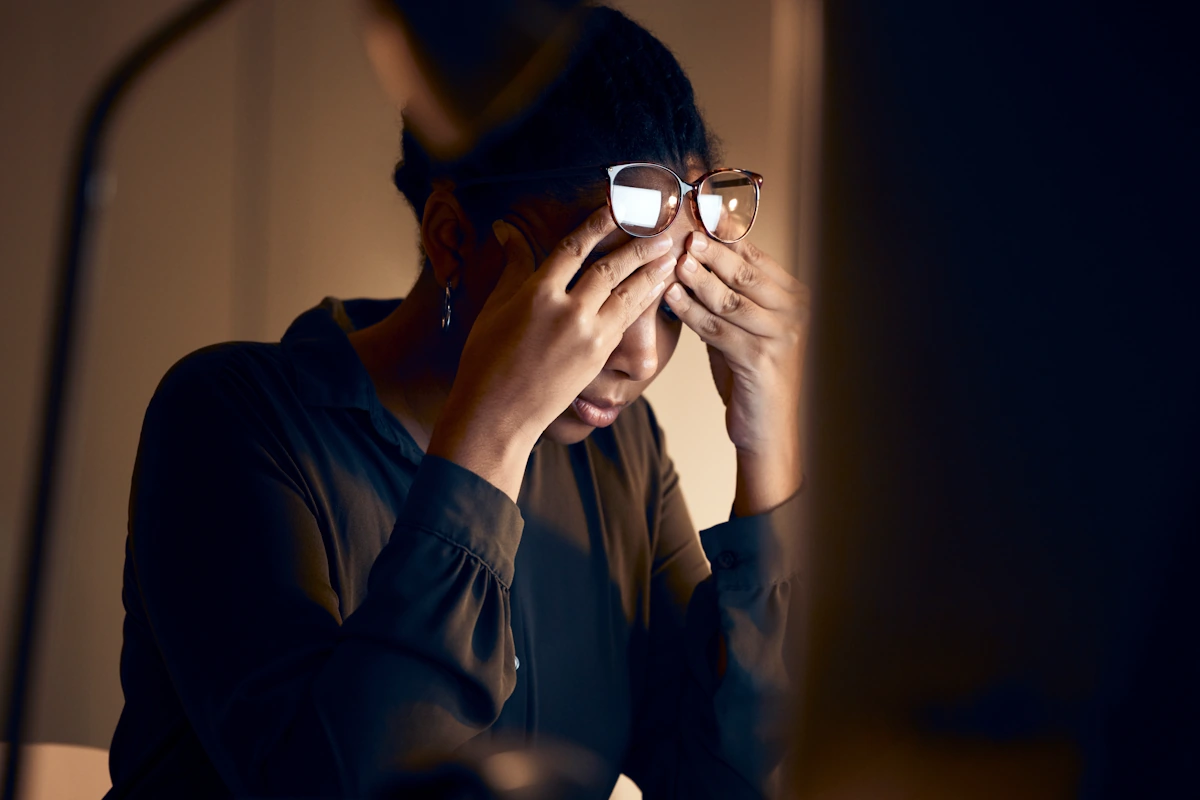 Une personne qui souffre de fatigue visuelle en tenant ses lunettes dans ses mains