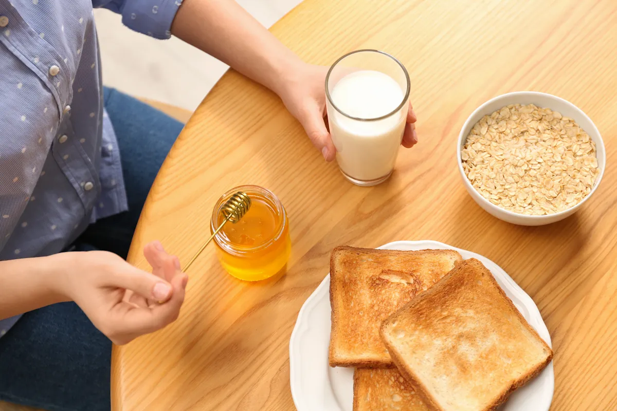 Une personne qui mange du pain blanc, jus de fruit, céréales sucrées