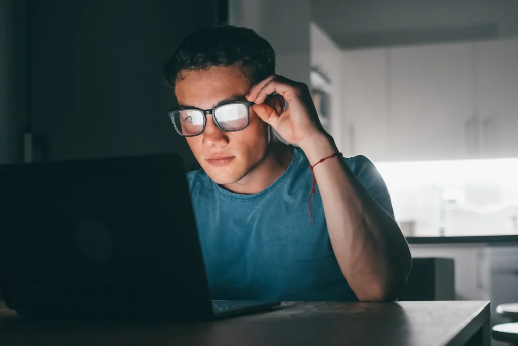 une personne qui porte des lunettes avec Verres anti-lumière bleue devant un ordinateur