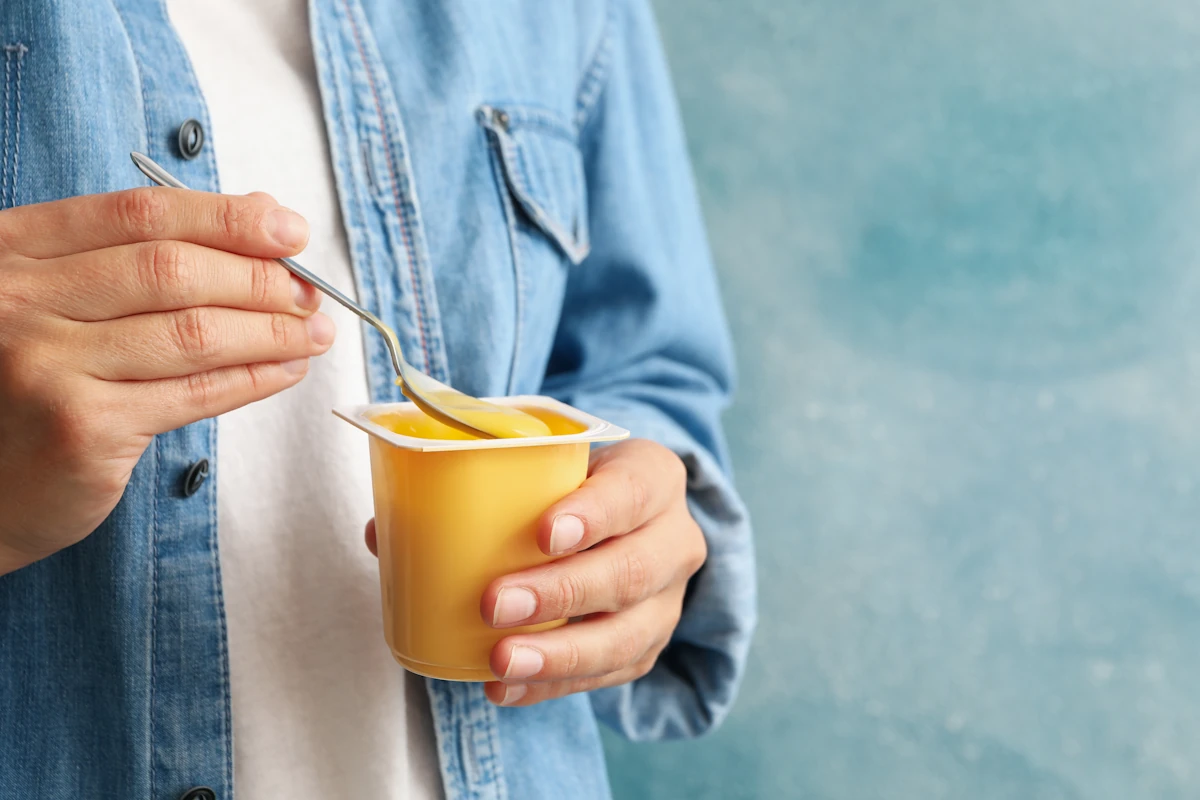 Une personne qui est en train de manger un yaourt parfumé sucré industriel