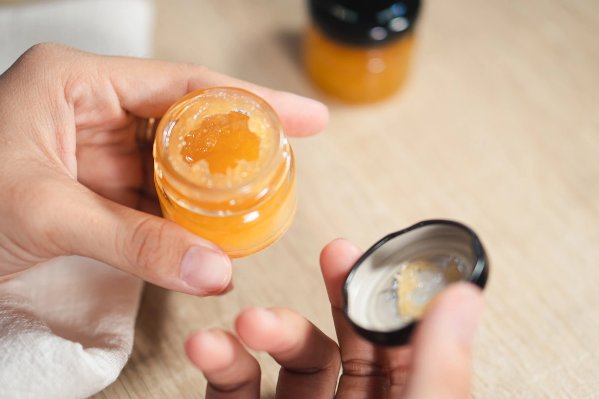 Une personne qui prend du miel pour le mettre sur une coupure