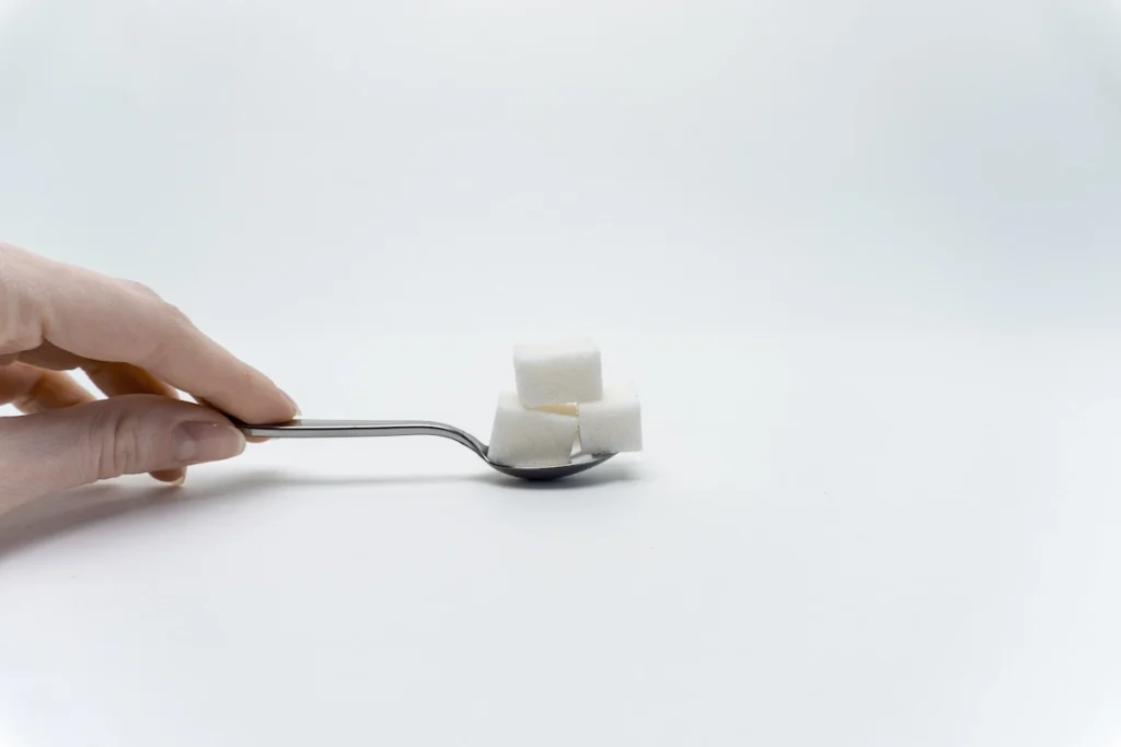 Une personne qui prend du sucre avec une cuillière