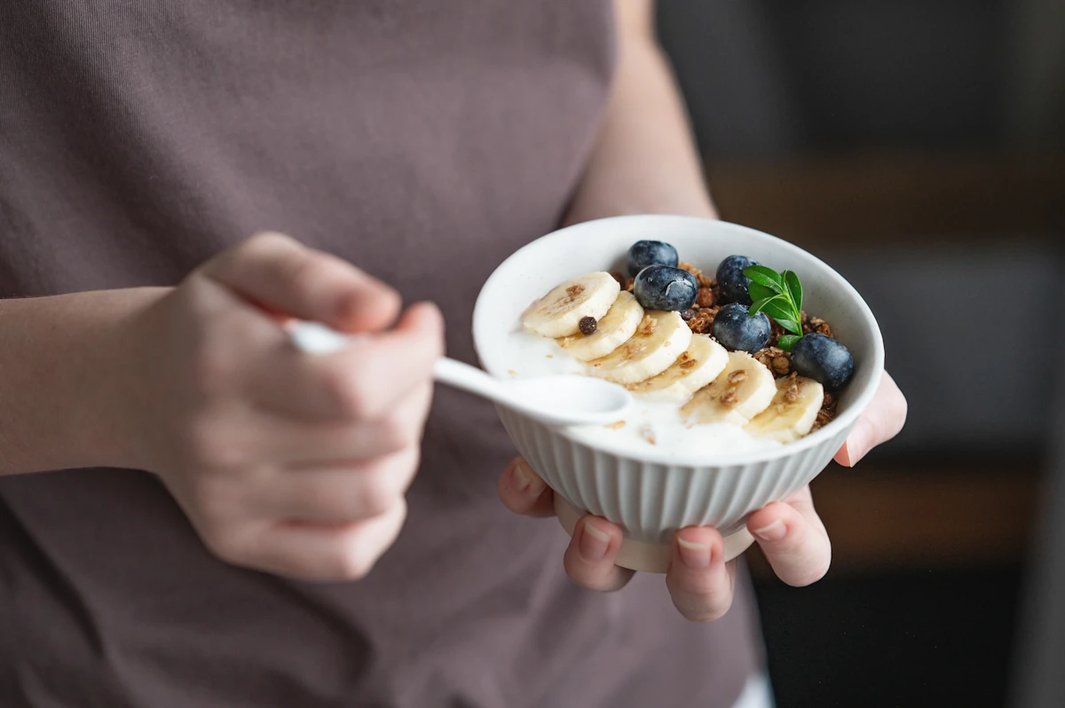 Une personne avec un bol de yaourt grec avec une banane